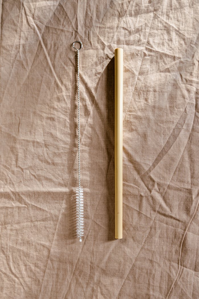 Bamboo straw with a metal cleaning brush on a beige textile background, eco-friendly products.